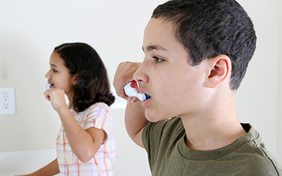 Two young children brushing teeth together